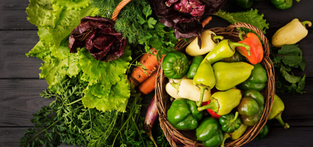 Assortment of vegetables and green herbs. Market. Vegetables in a basket on a dark background